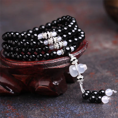 Natural red and black agate stone beaded bracelet with 108 geometric beads on a wrist.