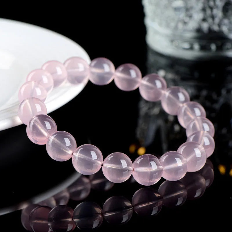 A polished natural starlight crystal round bead bracelet in pink, shown in a single circle design.