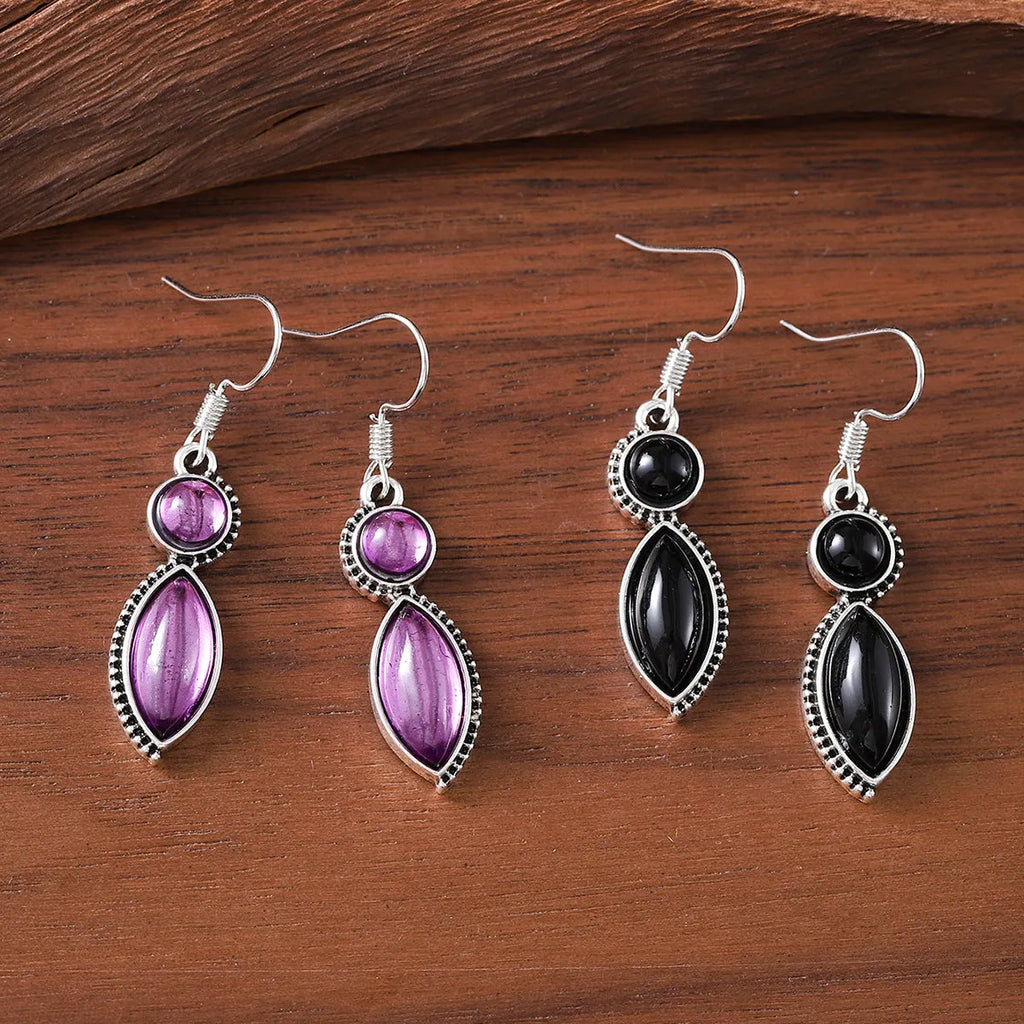 A pair of vintage geometric bohemian pendant earrings in black and purple with round design elements.