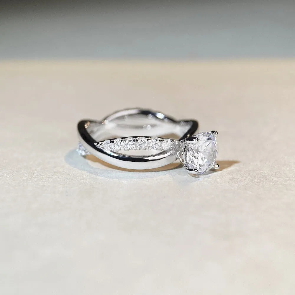 Silver geometric cross ring with a 1-karat moissanite stone on a twisted band.
