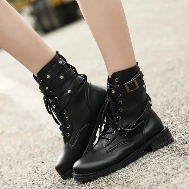 Women's black Martin motorcycle boots with low heel, lace-up front, round toe, and rivet and belt buckle detailing