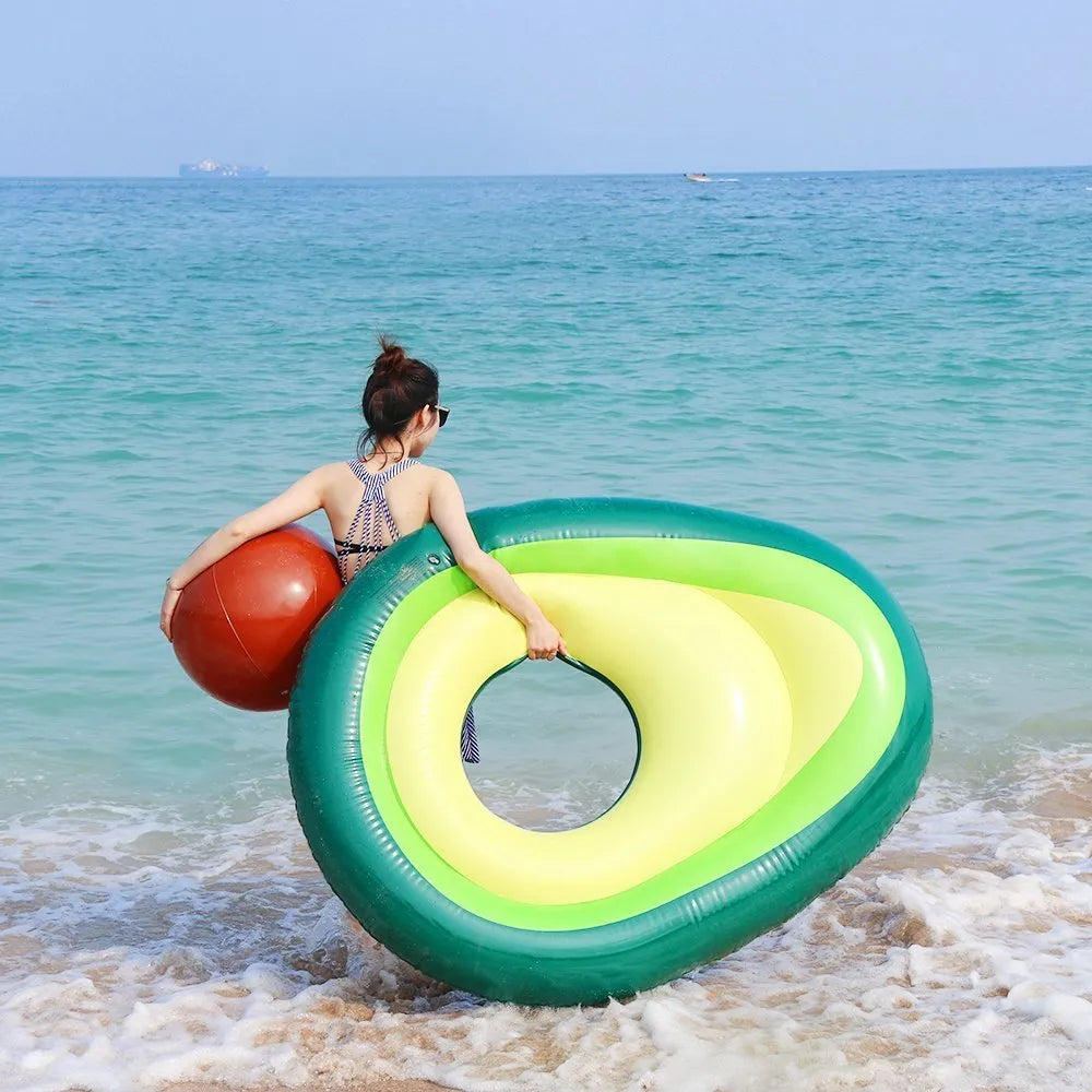 Large green inflatable avocado pool float on blue water.
