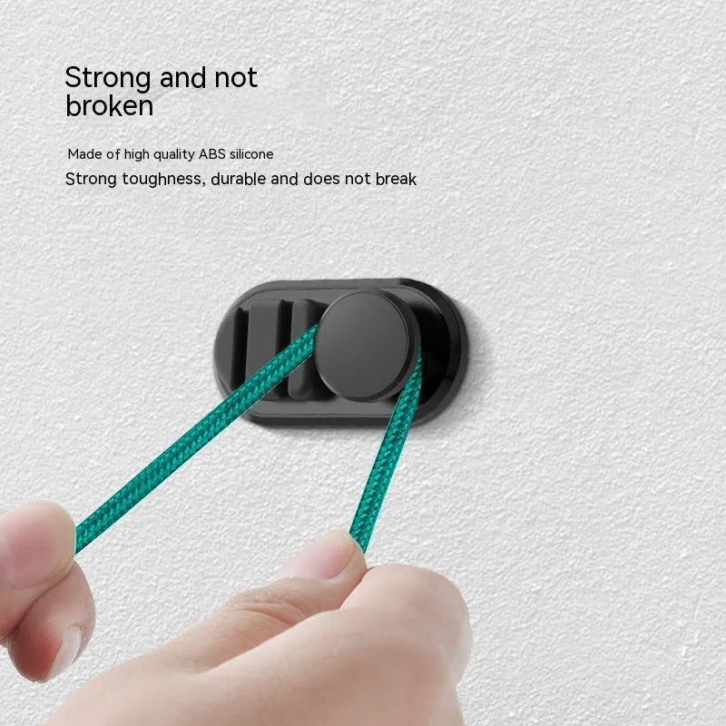 Dark green ABS silicone car cable hook with adhesive backing for organising data cables on a dashboard.