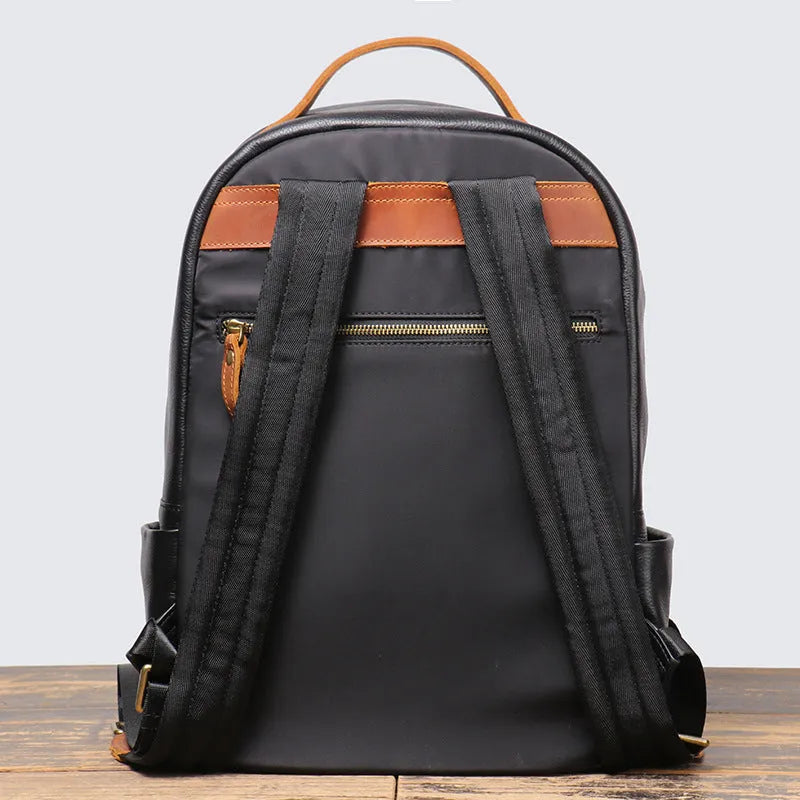 Black genuine leather expandable backpack with top grain cowhide, curved shoulder straps, and patchwork detail