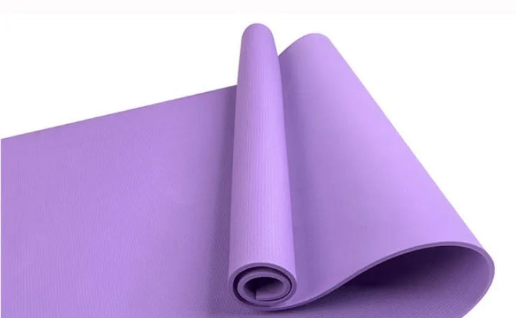Red EVA fitness yoga mat with rolled edge showing thickness, laid flat on a wooden floor.