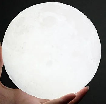 3D printed white moon lamp on wooden stand with touch-sensitive metal ring at base.