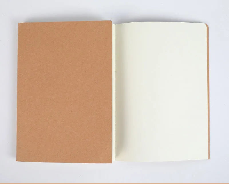 Softcover thread-bound notebook open on a table, showing flat-lay binding and lined paper.