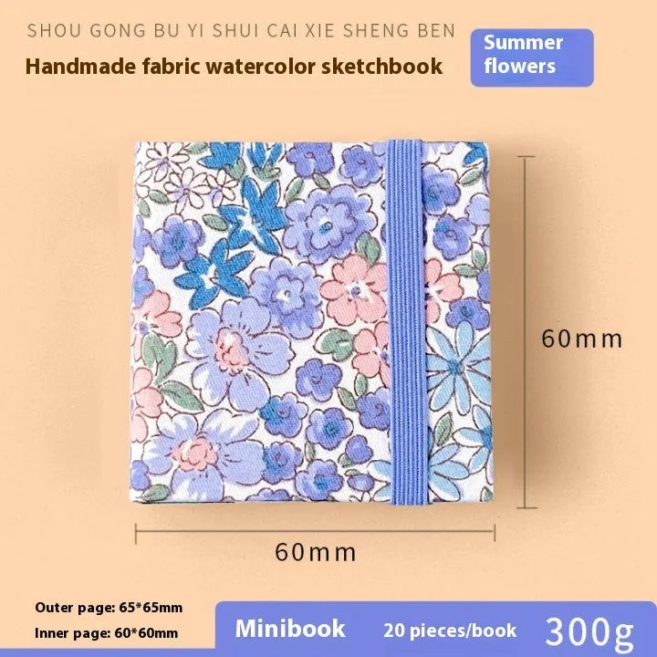 Feiluniao handmade fabric watercolour notebook with illustrated cover, open to show blank paper pages.
