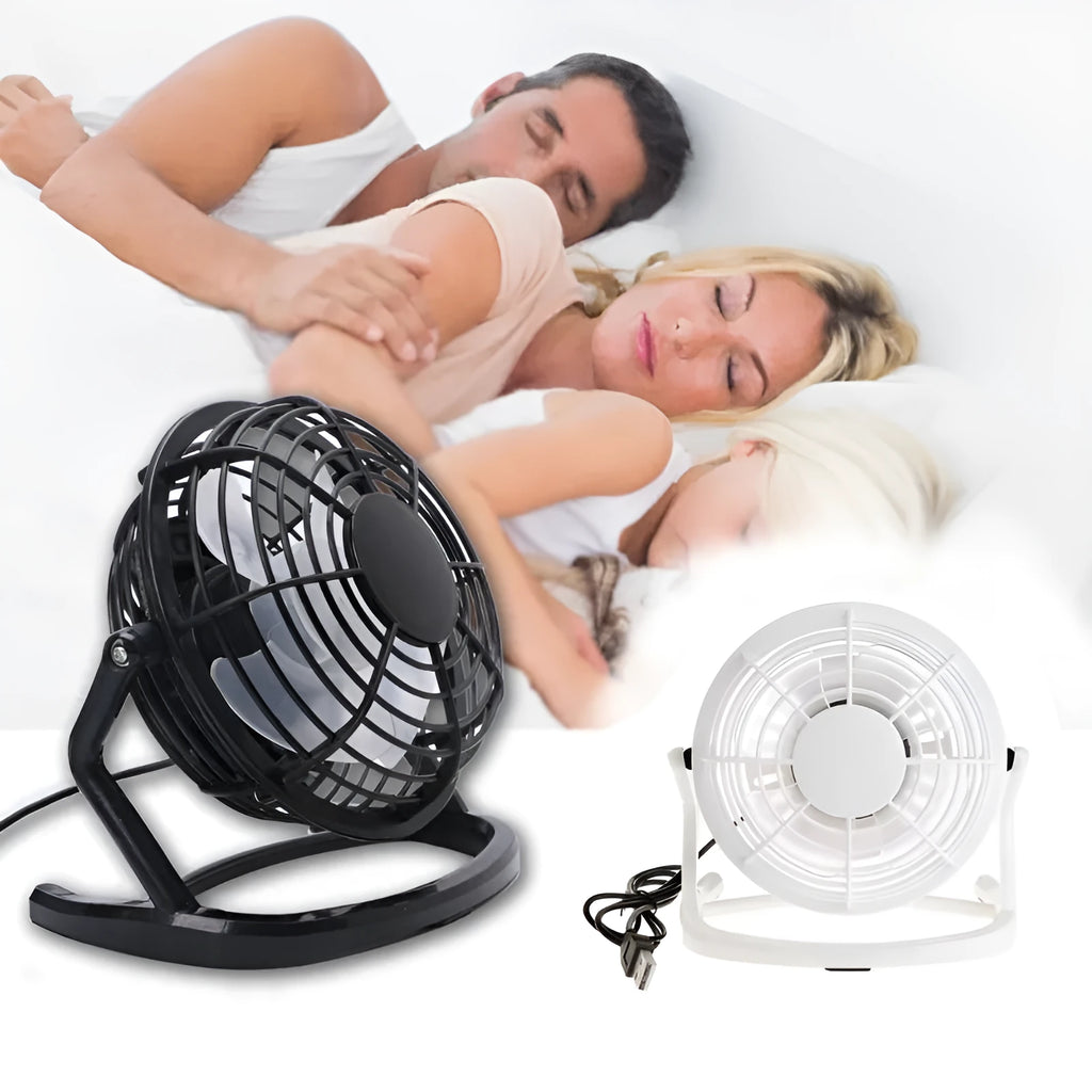 Small black USB desk fan with adjustable tilt on a wooden desk next to a laptop