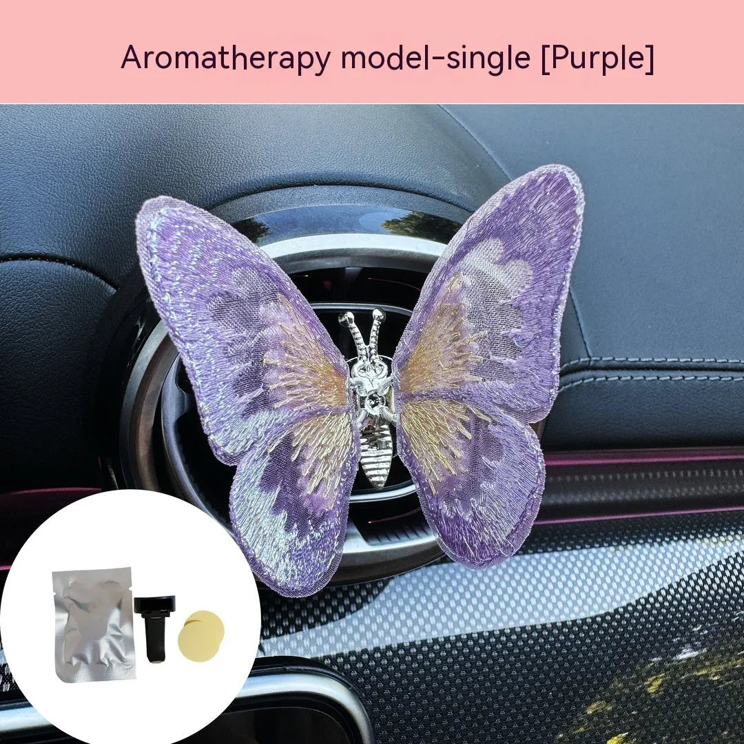 Fabric embroidered butterfly car air vent decoration in multiple colour options on a dashboard.