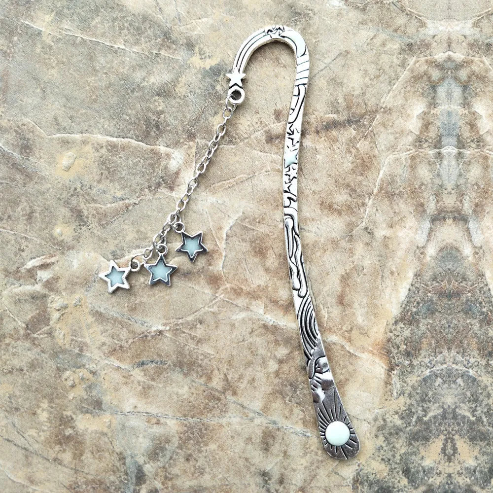 Metal bookmark with glowing five-pointed star and celestial sun moon stars design