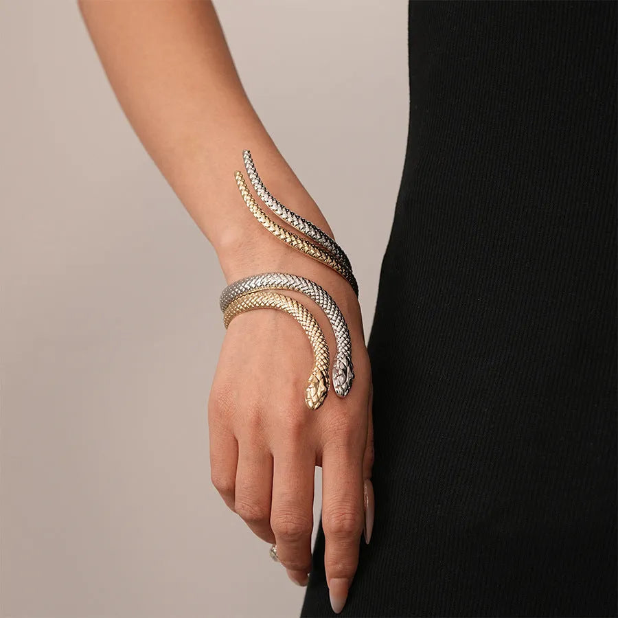 Gold exaggerated twisted snake design bracelet and ring jewellery set on a dark background.