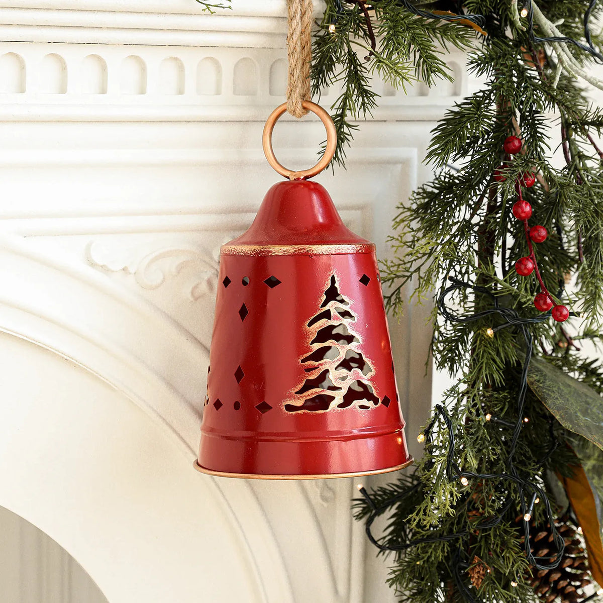 Wrought iron Christmas bell ornament in red, green, and white with hanging loop on a white background