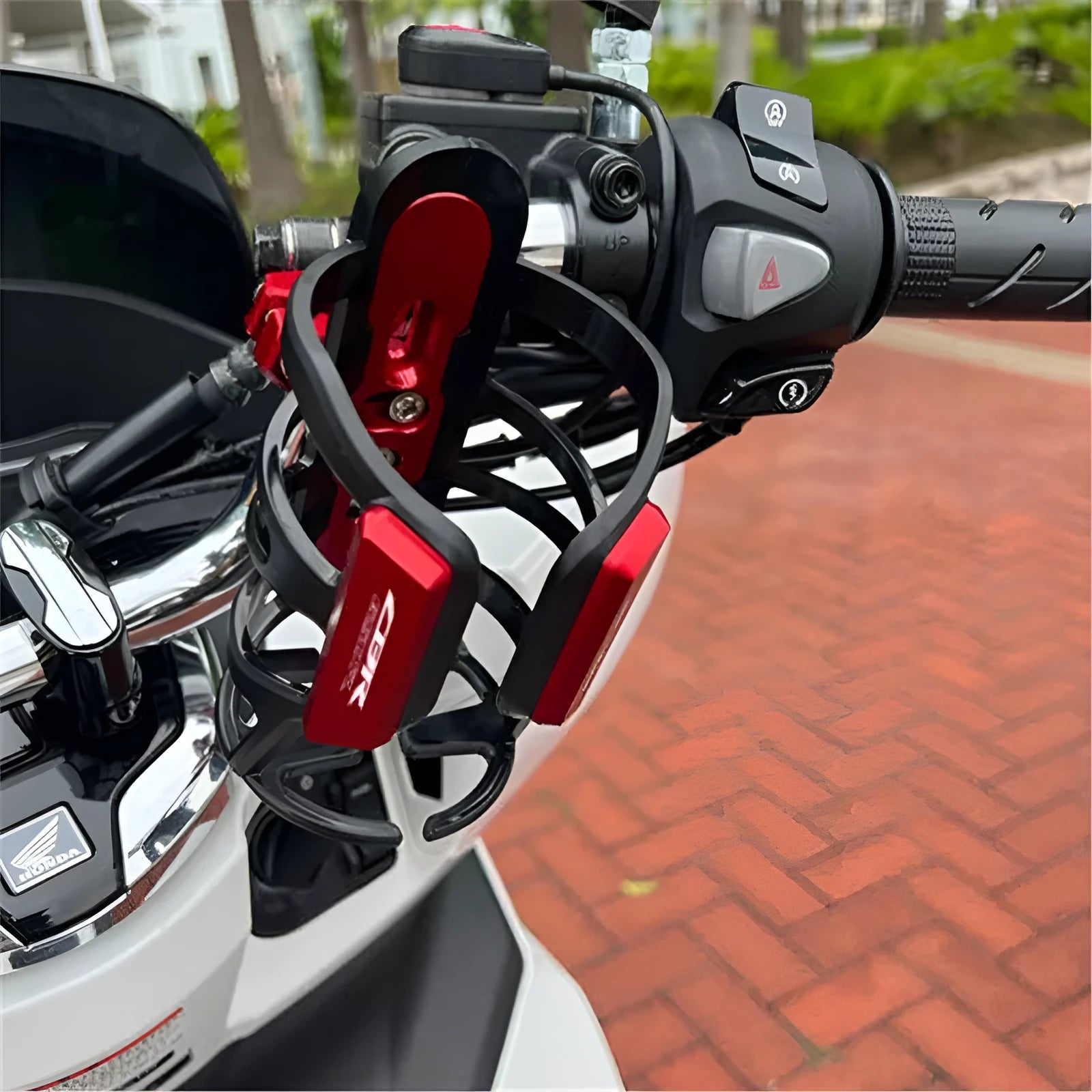 Black water bottle cage mounted on Honda scooter bumper with hydration bottle