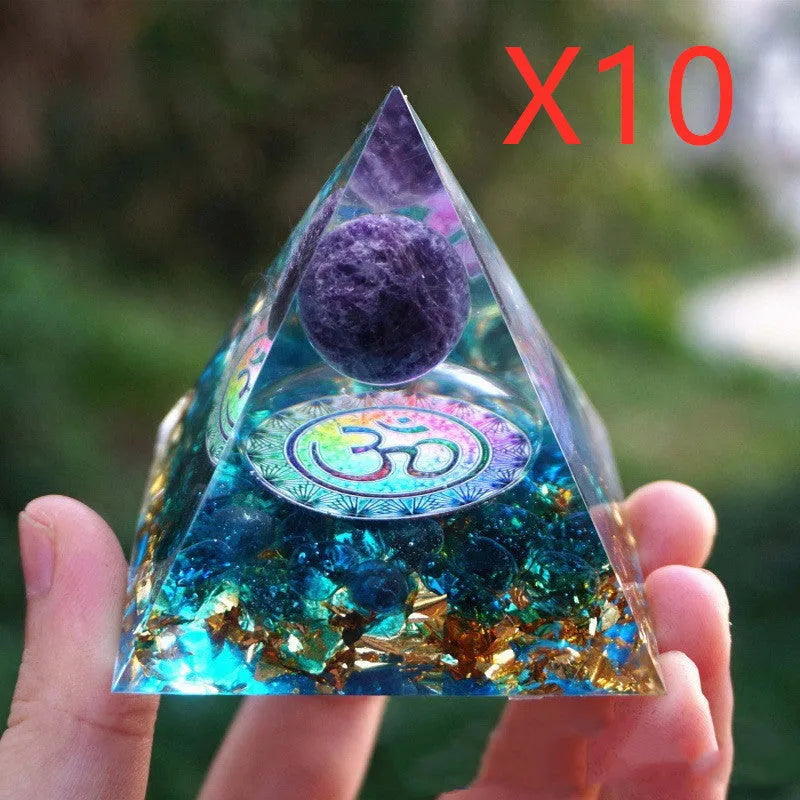 Clear epoxy resin pyramid ornament with natural crystal gravel inside on a wooden surface.