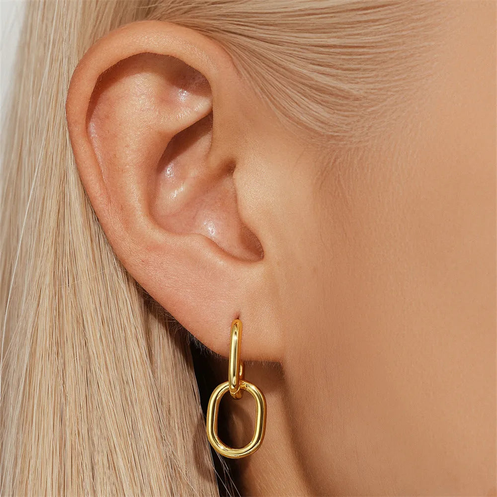 A pair of gold tone geometric earclip earrings with a round design and screw-back mechanism.
