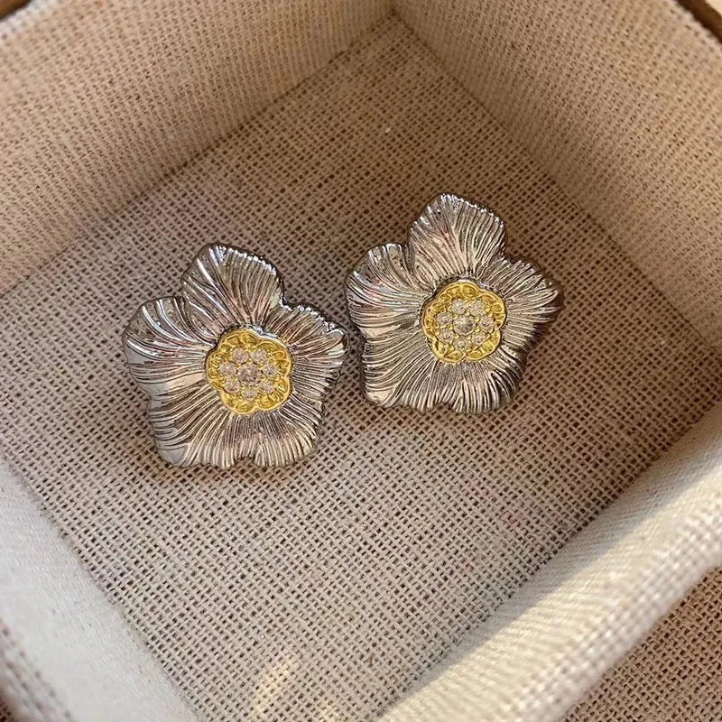 Close-up of women's copper stud earrings with a textured floral design in a two-tone colour.
