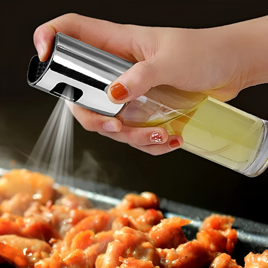 Gold pump-action oil and vinegar spray bottle with 100ml glass body on kitchen counter.