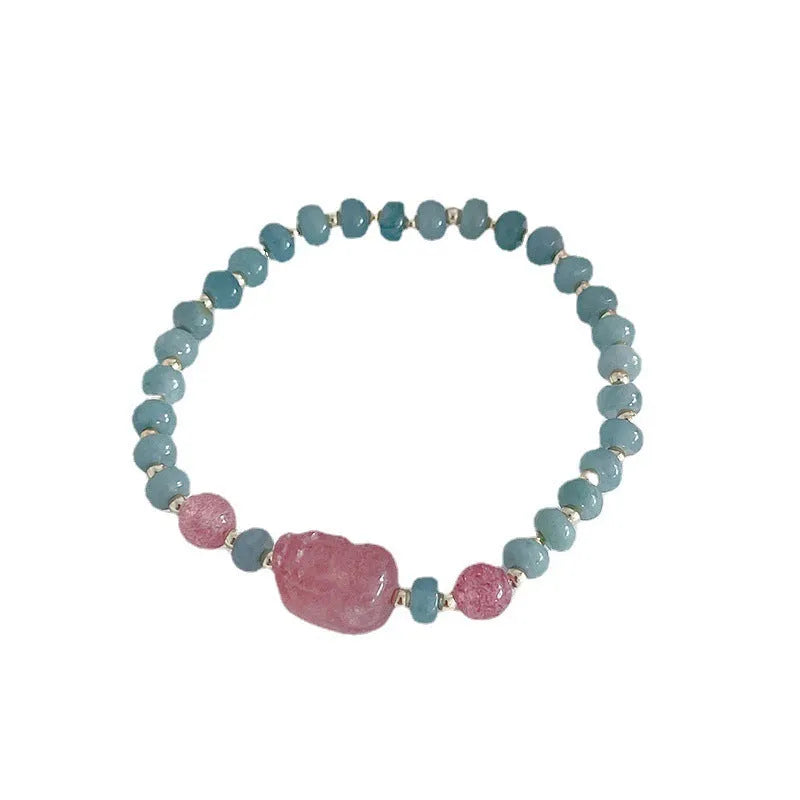Close-up of a blue jade women's bracelet showing a gourd charm and a peace buckle charm on a string.
