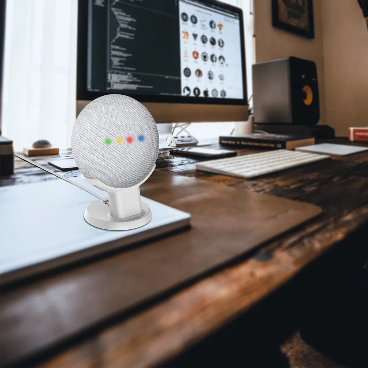 Black PlusAcc plastic stand holding a white Google Home Mini smart speaker on a wooden tabletop.