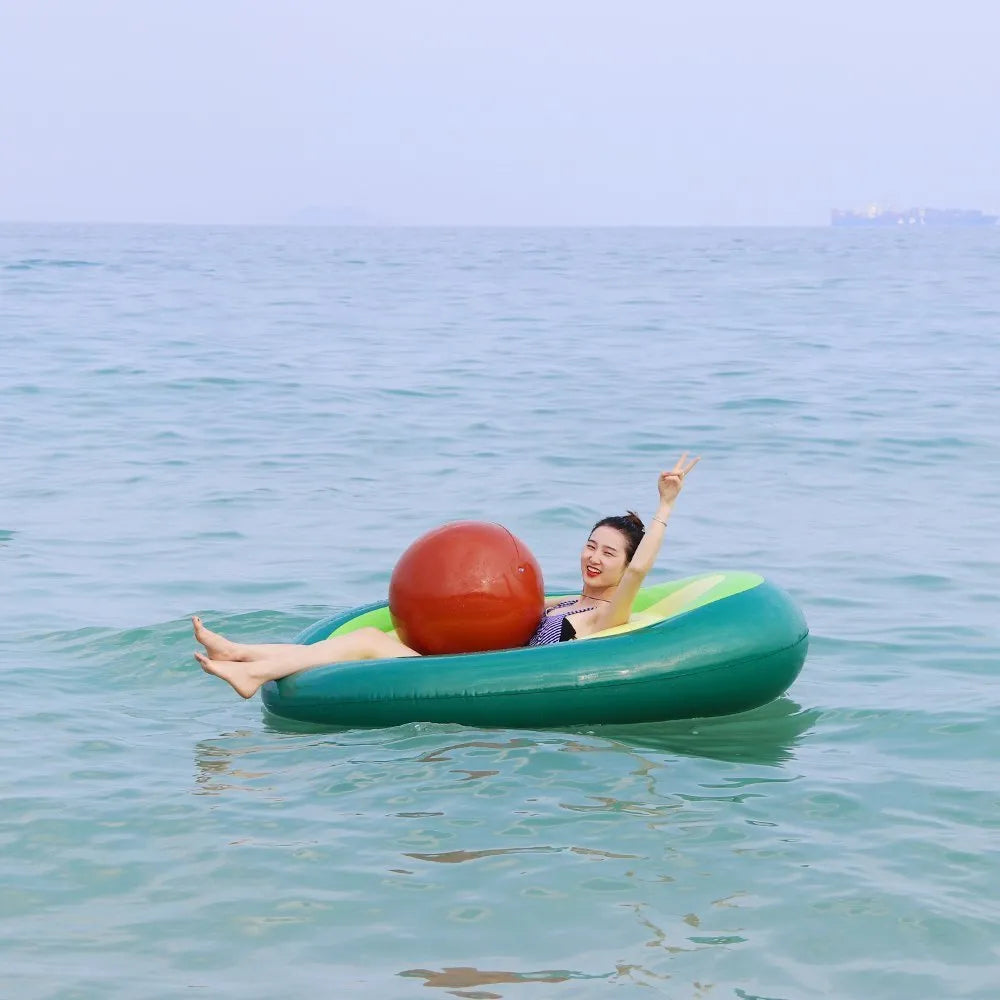Large green inflatable avocado pool float on blue water.