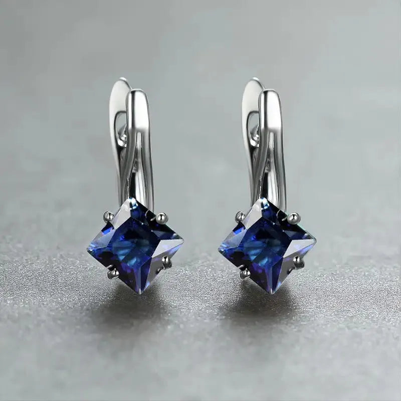 A pair of copper diamond-shaped earrings with inlaid zircon stones, shown in blue, green, and colour variants.