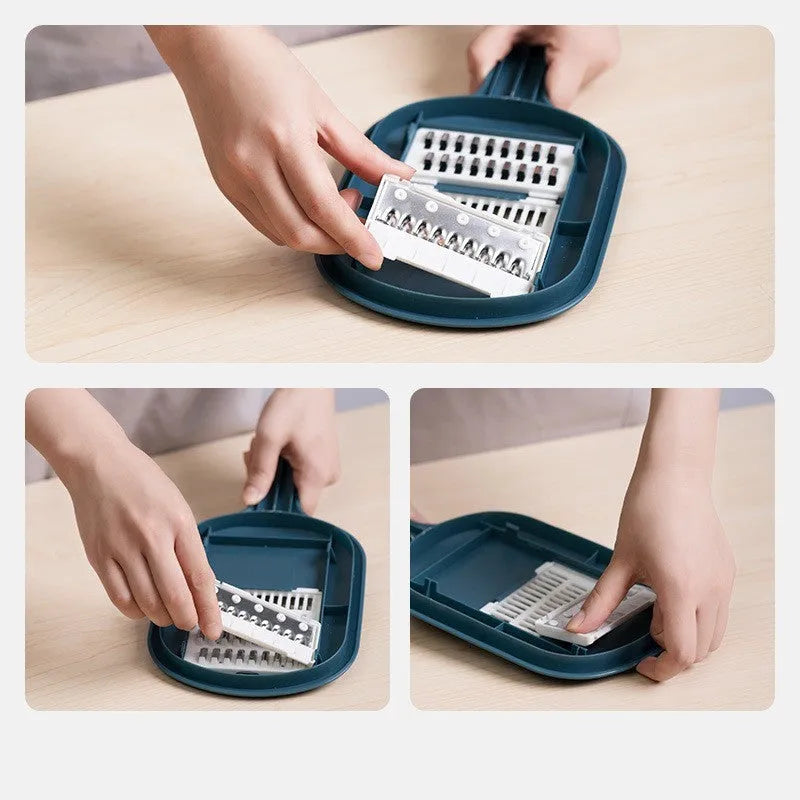 Dark blue vegetable cutter with four stainless steel blades, a drain basket, and a hand guard on a kitchen counter.