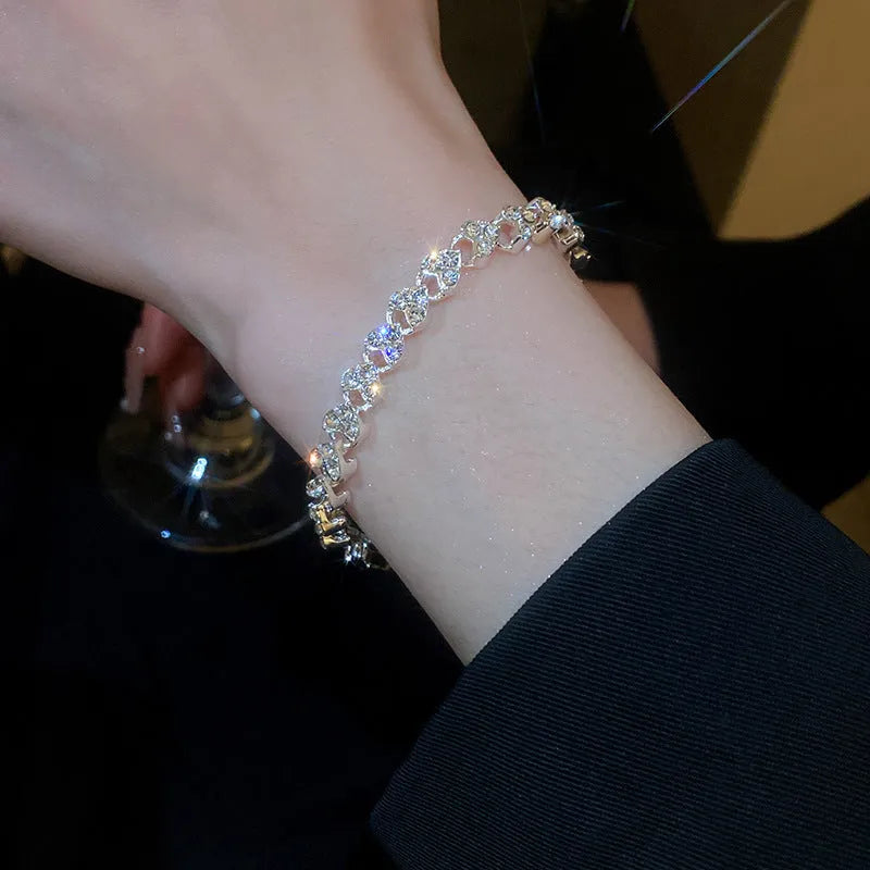 Silver metal heart-shaped bracelet with inlaid zircon on a plain background