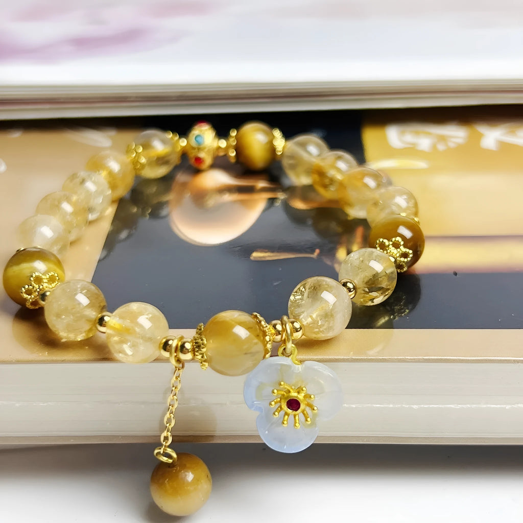 Women's citrine crystal bracelet with gold-plated flower tassel design on wrist.