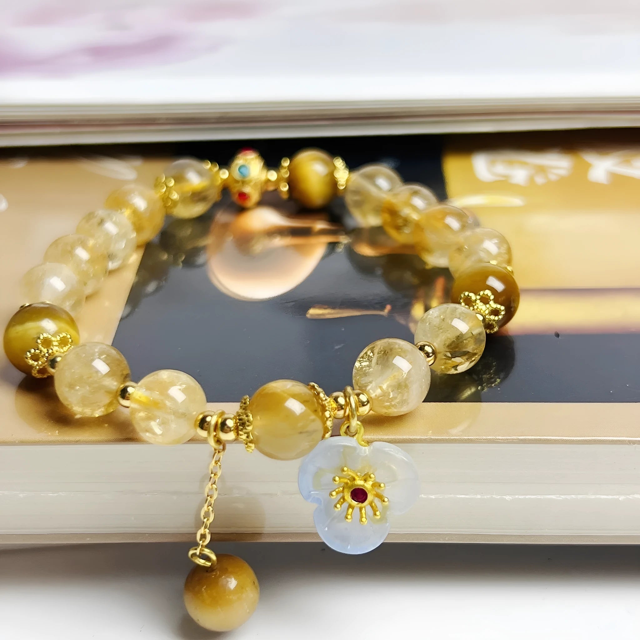 Women's citrine crystal bracelet with gold-plated flower tassel design on wrist.