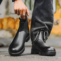 Vintage frosted brown leather Chelsea boots with round toe and car suture detailing on a wooden floor.