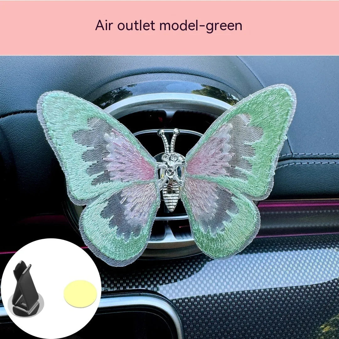 Fabric embroidered butterfly car air vent decoration in multiple colour options on a dashboard.