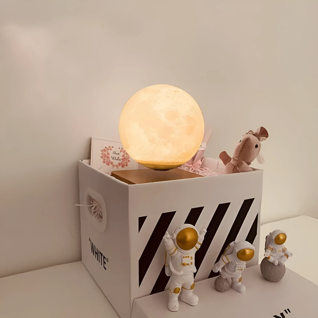 Moon planet floating LED night light with three astronaut figurines on dark surface