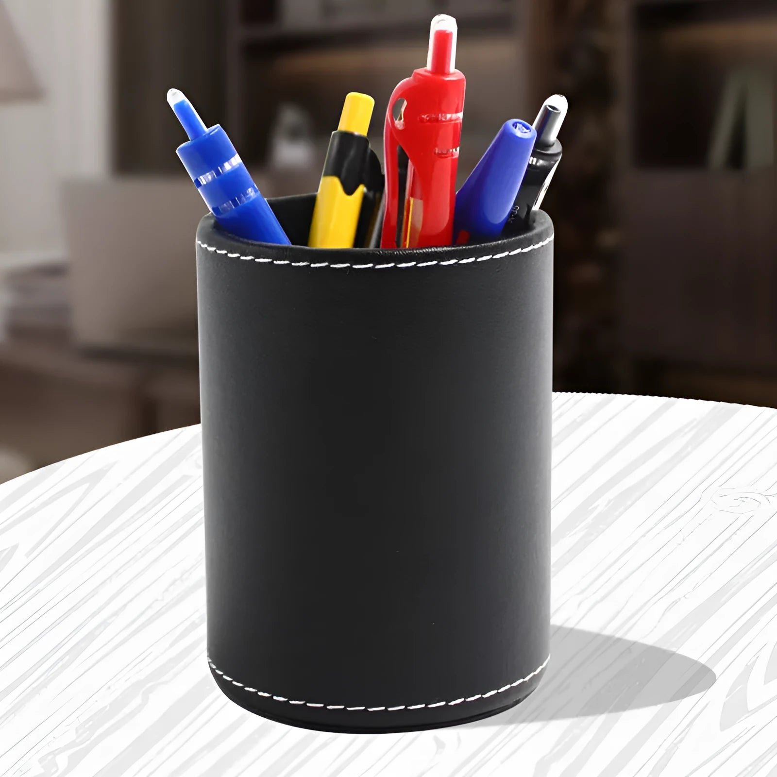 Black leather round pen container on desk with dimensions 8.0cm diameter 10.8cm height