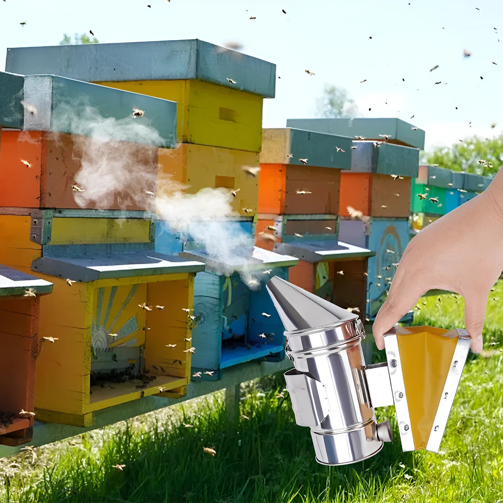 Stainless steel bee smoker with leather bellow on a wooden table against a blurred outdoor background