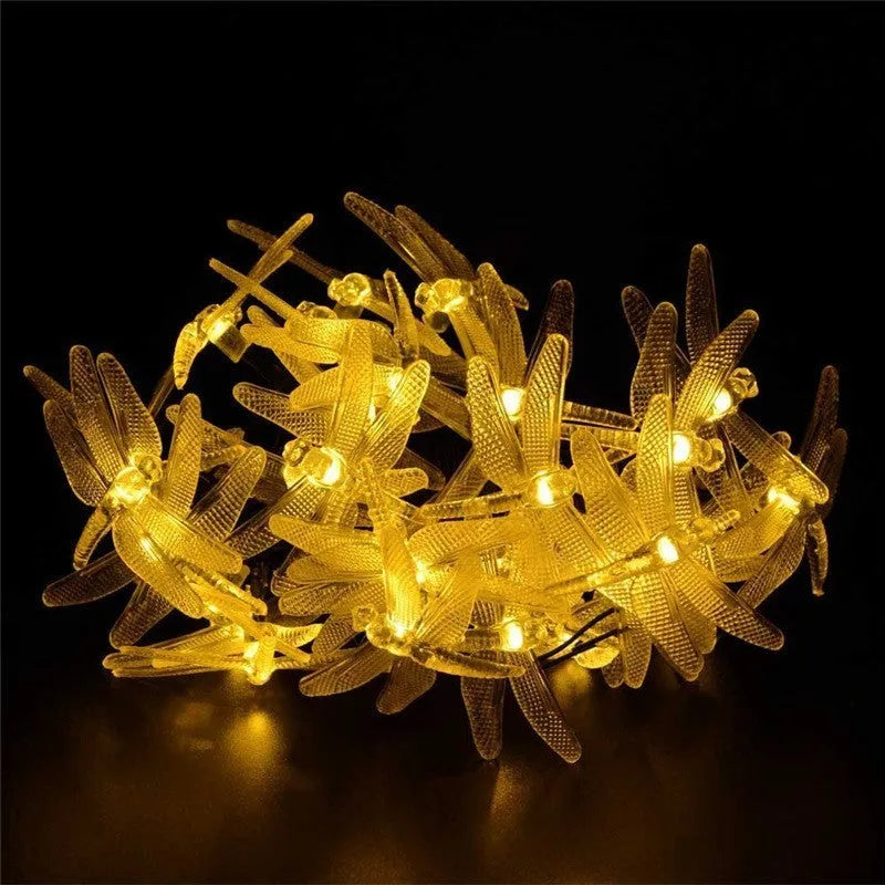 Outdoor solar LED dragonfly string lights with warm white bulbs on a 5-metre cable and a ground-spike solar panel.