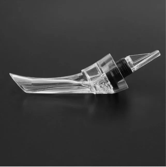 A clear acrylic wine aerator with a stainless steel filter, shown next to a wine glass.