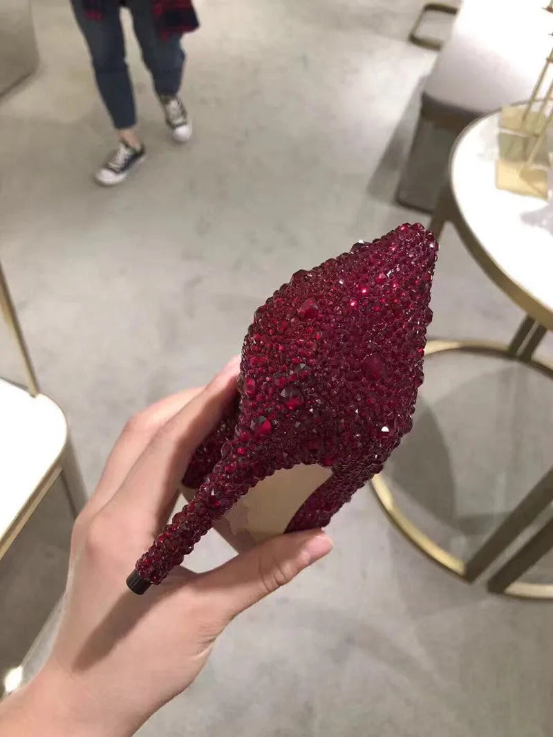 Gold women's pointed toe high heels with rhinestone and sequin decorations on a stiletto heel.