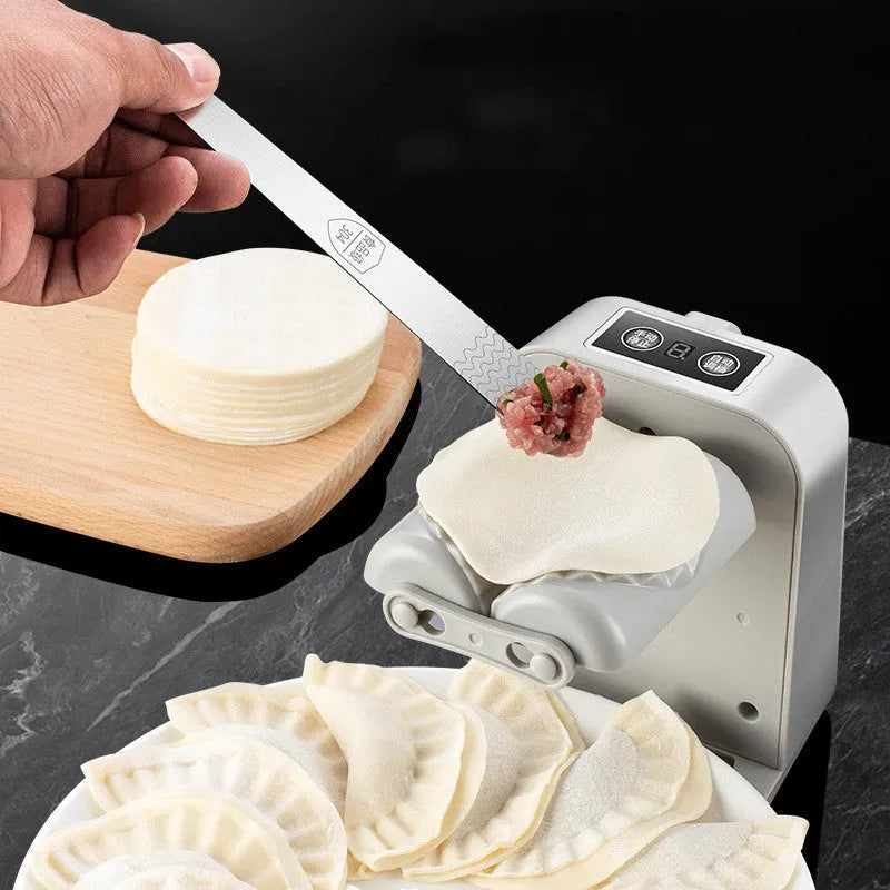 White automatic electric dumpling maker machine with charging cable, brush, and spoon.