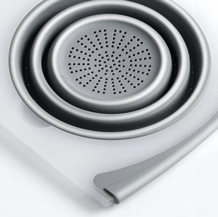 Grey 3-in-1 chopping board with detachable folding drain basket on a kitchen counter.