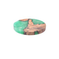 Wooden coaster with heat insulation resin in round tumour green colour on a table.