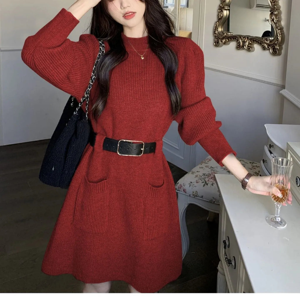 Women's long sleeve loose knitted dress in beige with a black belt, shown on a hanger.