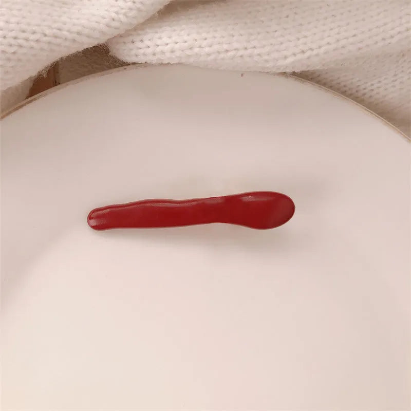 Red love heart-shaped plastic hair clip with retro dots and a willow leaf silhouette on a white background.