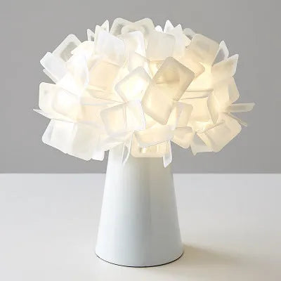 Nordic style decorative table lamp with metal base in a choice of colours on a bedside table.