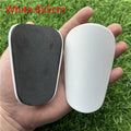Pair of extra small black and white plastic football shin guards, measuring 8cm by 5cm.