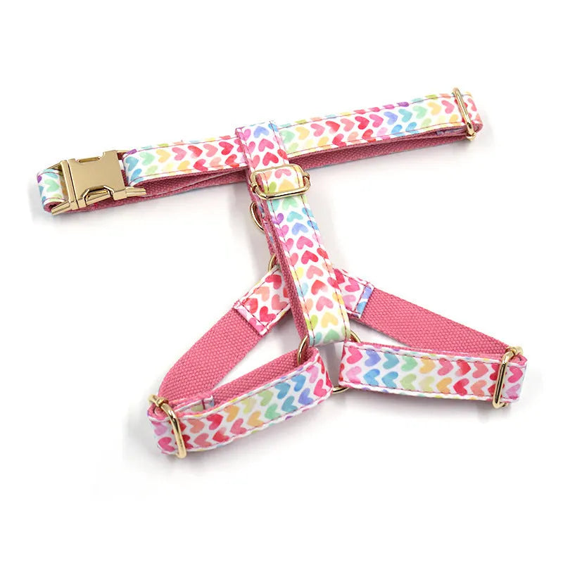 Pink dog harness with a gold buckle and colourful heart-shaped stone decoration on an adjustable polyester strap.