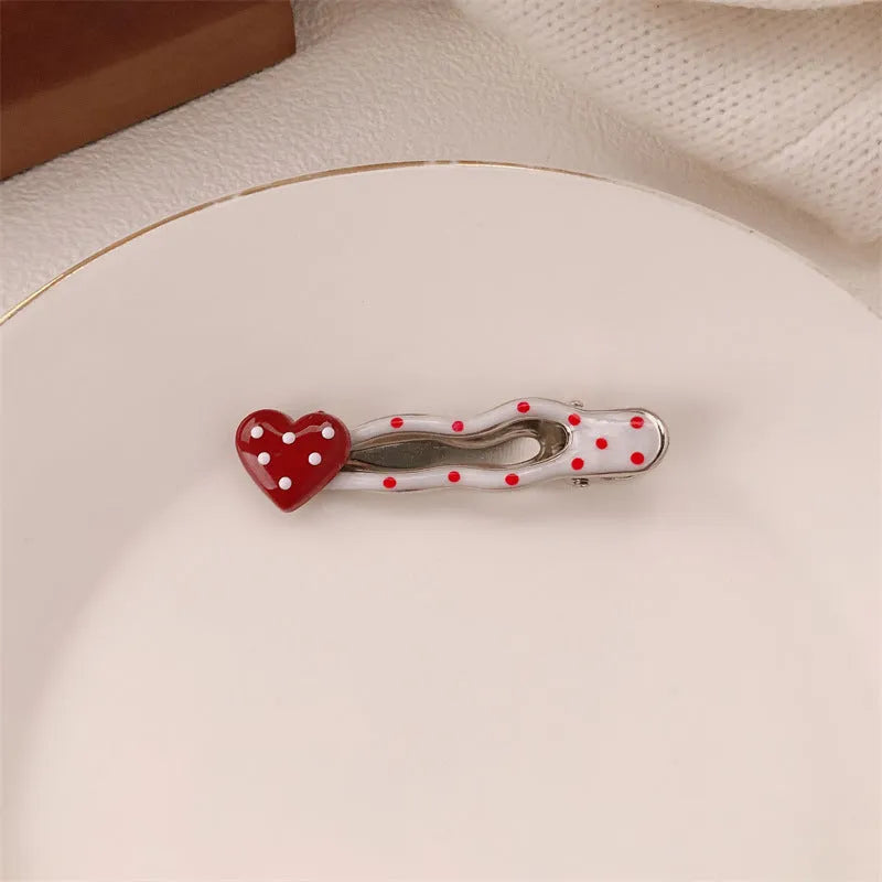Red love heart-shaped plastic hair clip with retro dots and a willow leaf silhouette on a white background.