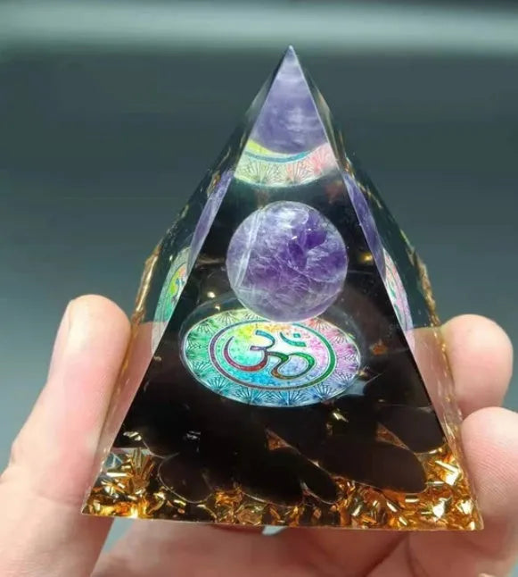 Clear epoxy resin pyramid ornament with natural crystal gravel inside on a wooden surface.