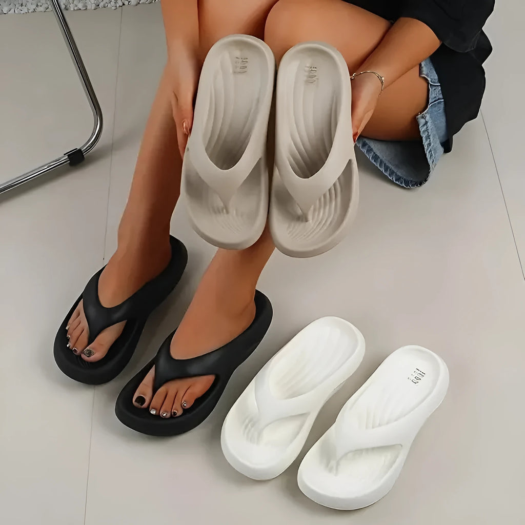 A pair of women's thick-soled flip-flops in grey, showing the EVA material and non-slip footbed texture.