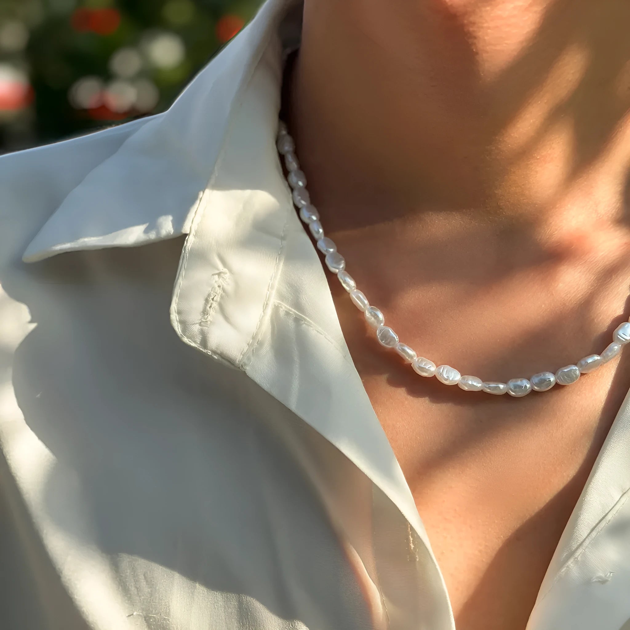 White U-shaped men's imitation pearl necklace with shellfish pendant on pearl chain.